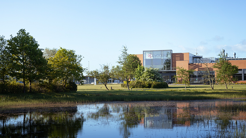 Una vista del edificio de Kyocera Unimerco en Sunds desde el exterior, junto a un lago cercano a la empresa.